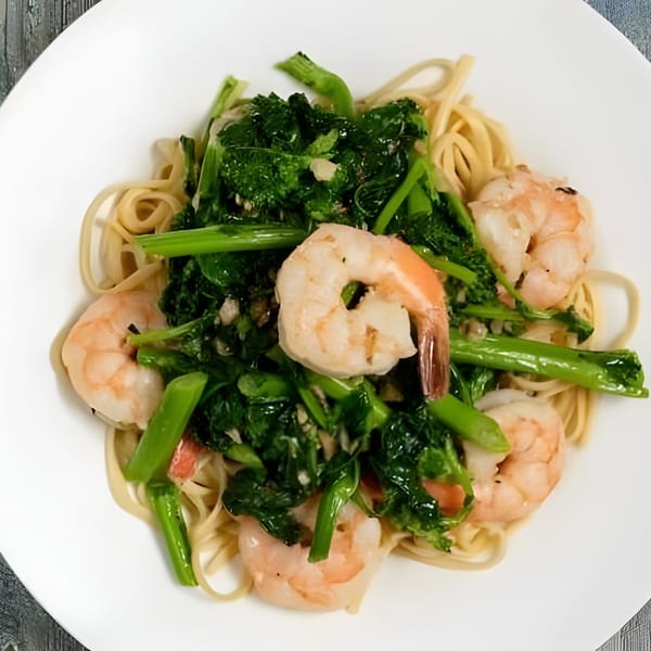 Sage Restaurant's shrimp scampi with linguine pasta, broccoli rabe, and garlic on a white plate.