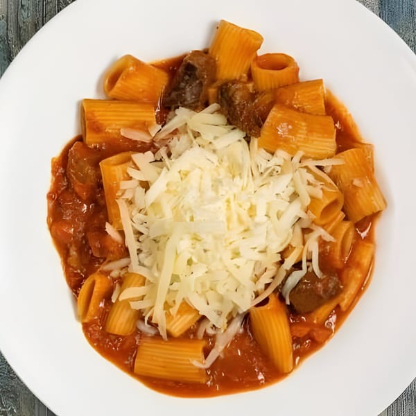 Rigatoni pasta with meat sauce and shredded cheese on a white plate.